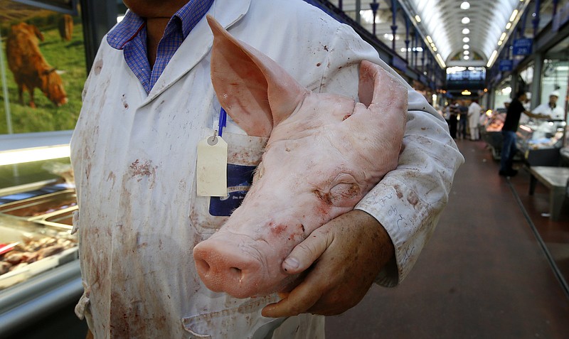 
              In this photo taken on Monday, July 18, 2016, a butcher carries a pigs head at Smithfield Market in London. Welsh farmers like Rees Roberts, who have 1,000 acres with sheep, cattle and crops, can expect to earn a premium on their meats thanks to a certificate of regional authenticity. But that marker of distinction _ the same kind that ensures Champagne can only come from the French region of the same name _ is granted by the European Union and is now at risk after Britain voted to leave the 28-country bloc. (AP Photo/Kirsty Wigglesworth)
            