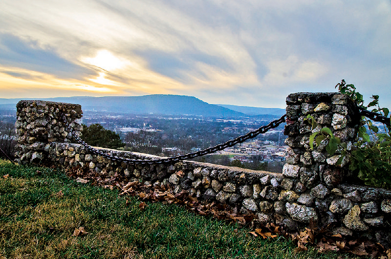 A stone wall sits on Missionary Ridge with Chattanooga, Lookout Mountain and the setting sun in the background Sunday.