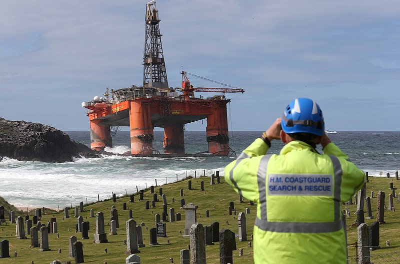
              A coastguard official monitors the Transocean Winner drilling rig off the coast of the Isle of Lewis, Scotland, after it ran aground in severe weather conditions, Tuesday Aug. 9, 2016.  The oil rig, carrying 280 tonnes of diesel, broke free of its tug and ran aground on the remote Scottish island where it is being monitored by a counter-pollution team.  (Andrew Milligan / PA via AP)
            