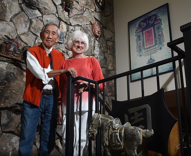 Dr. Jackson Joe Yium, and his wife, Milli Yium, stand in the foyer of their home on Signal Mountain. The framed art, at right, is a mural of his family home in Toisin, China. 