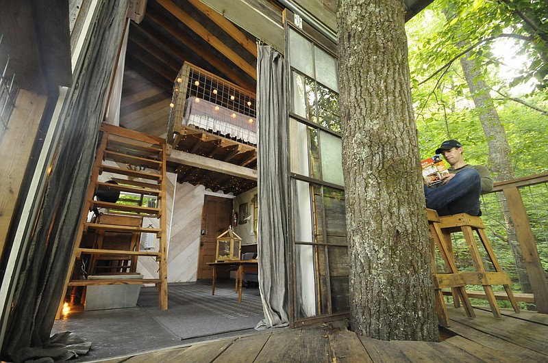 Andrew Alms sits outside on the deck of the treehouse.