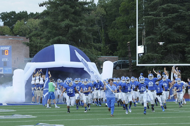 The McCallie football team runs onto the field from out of a new inflatable blue helmet.