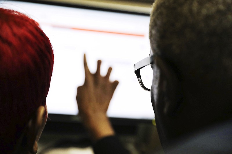 
              FILE - In this Thursday, March 3, 2016, file photo, Georgia Department of Labor services specialist Louis Holliday, right, helps a woman with a job search on a computer at an unemployment office in Atlanta. On Thursday, Aug. 11, the Labor Department reports on the number of people who applied for unemployment benefits in the previous week. (AP Photo/David Goldman, File)
            