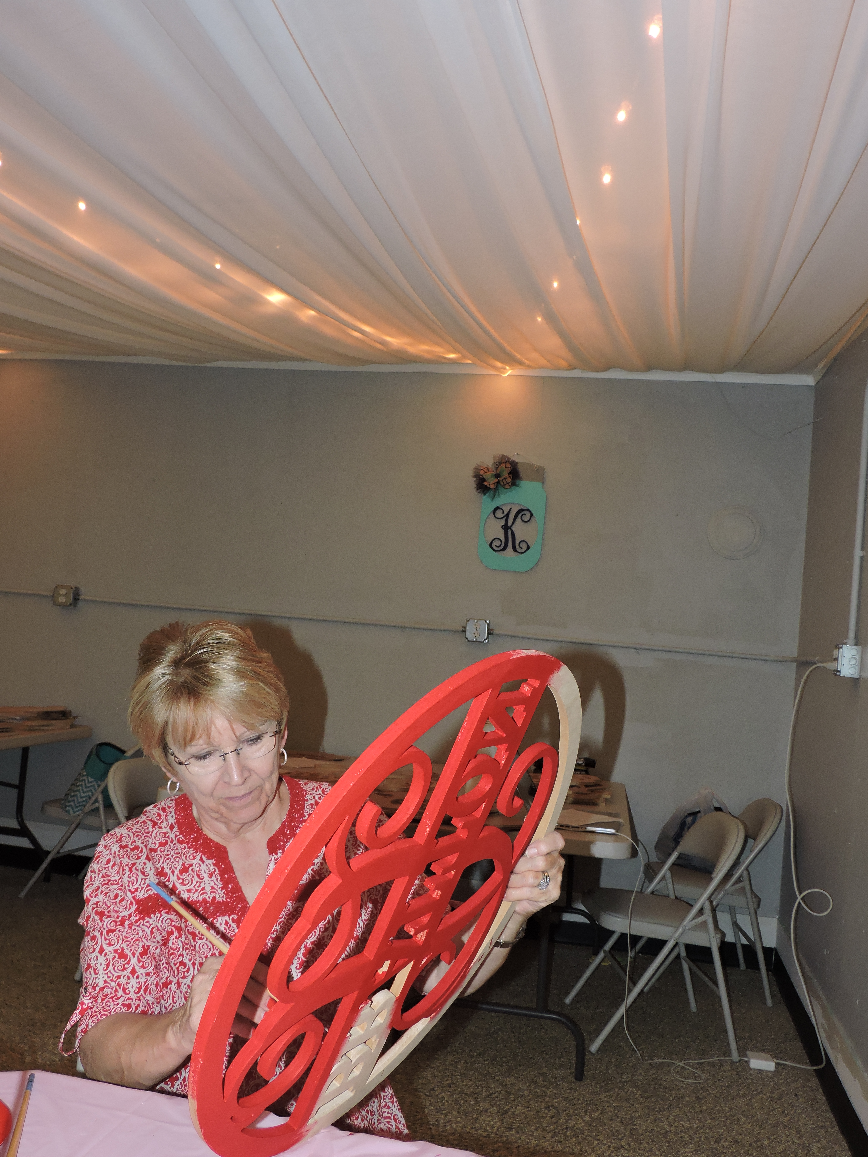 Red Barn Designs shop vendor/painter Lillie Nash paints a door hanger that bears the initials of the purchaser.