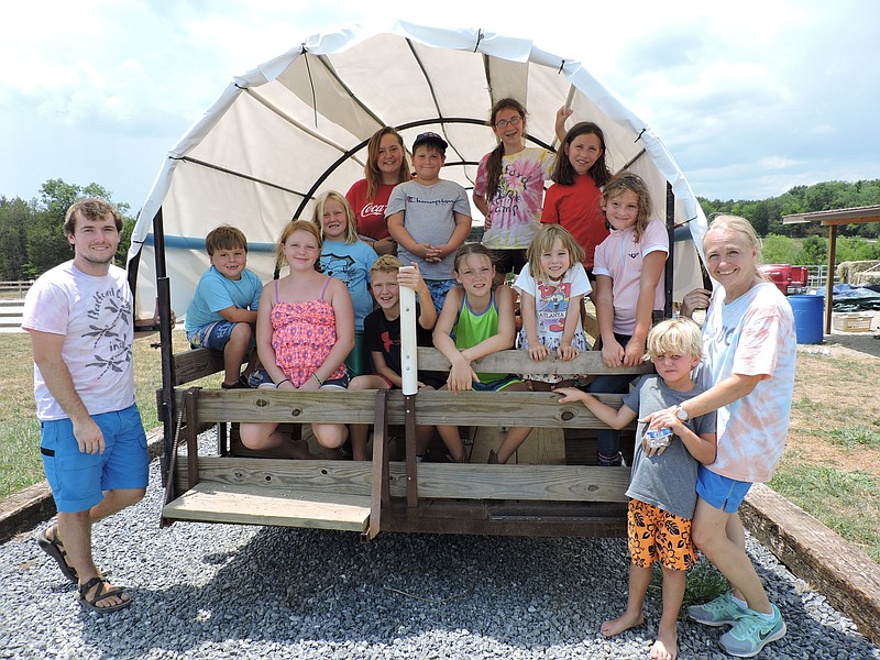 Front from left are Bradford Camp manager Bret Bradford, camper Charlie Pace and Bradford Camp co-owner Alisa Bradford. In back are Bradford Camp campers inside the covered wagon built by Tommy Hise, affectionately called Grandpa by all campers.
