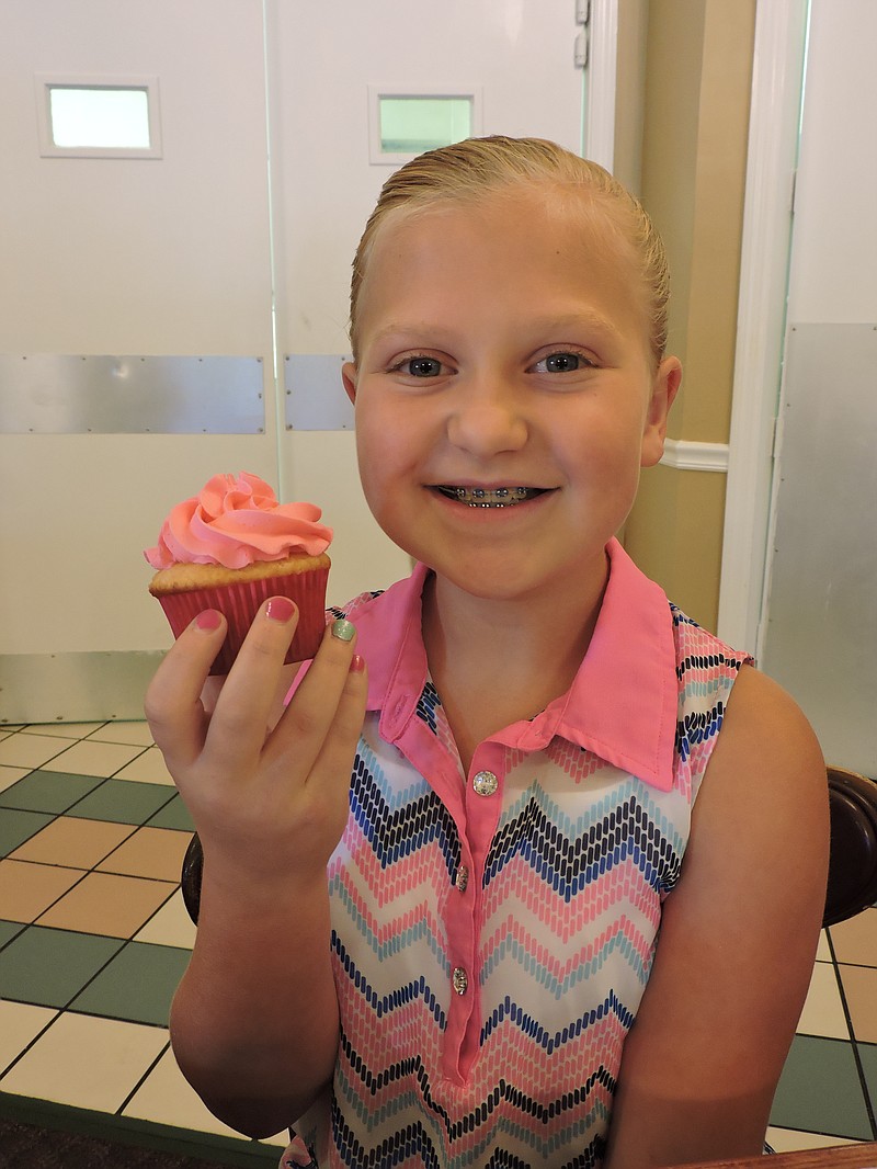 KK's Sweet Treats owner Kaitlyn Helton, 11, holds one of her personally made cupcakes.