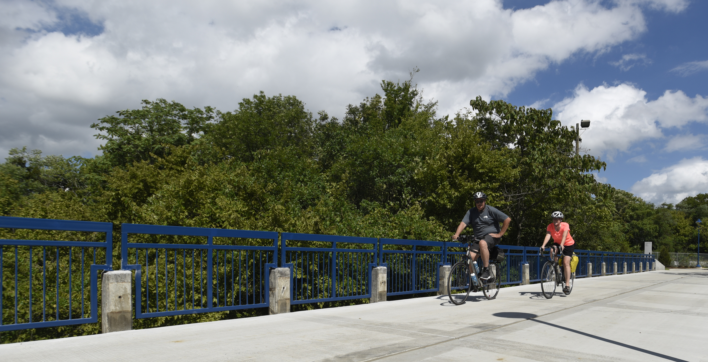 Cyclists cross a bridge on the newly-opened section of the Riverwalk Friday, August 12, 2016.