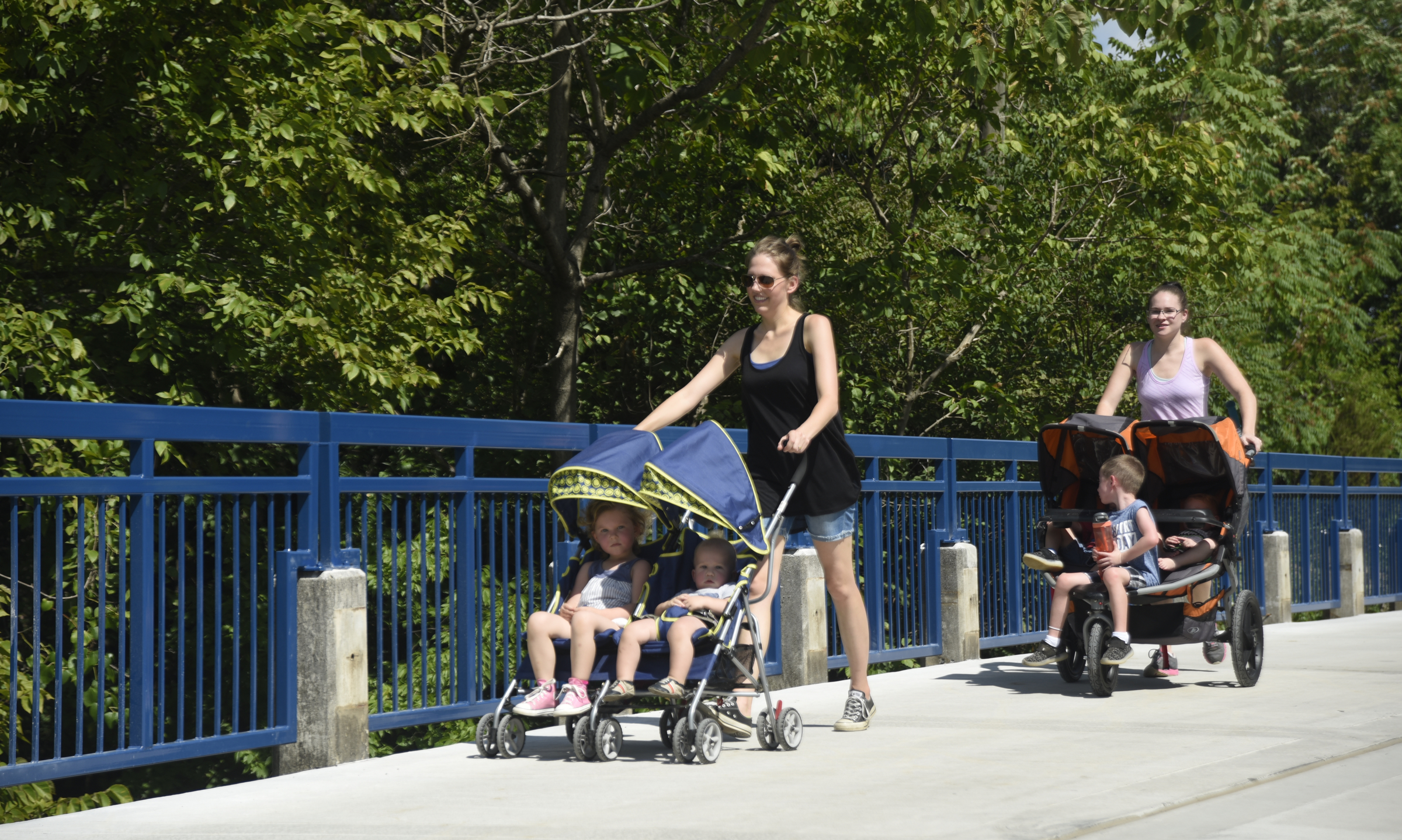 Becca Pouliot pushing Noah and Olive, and Stephanie Heramb, pushing Lucas, Jacob and Judah, cross a bridge on the newly-opened section of the Riverwalk Friday, August 12, 2016.