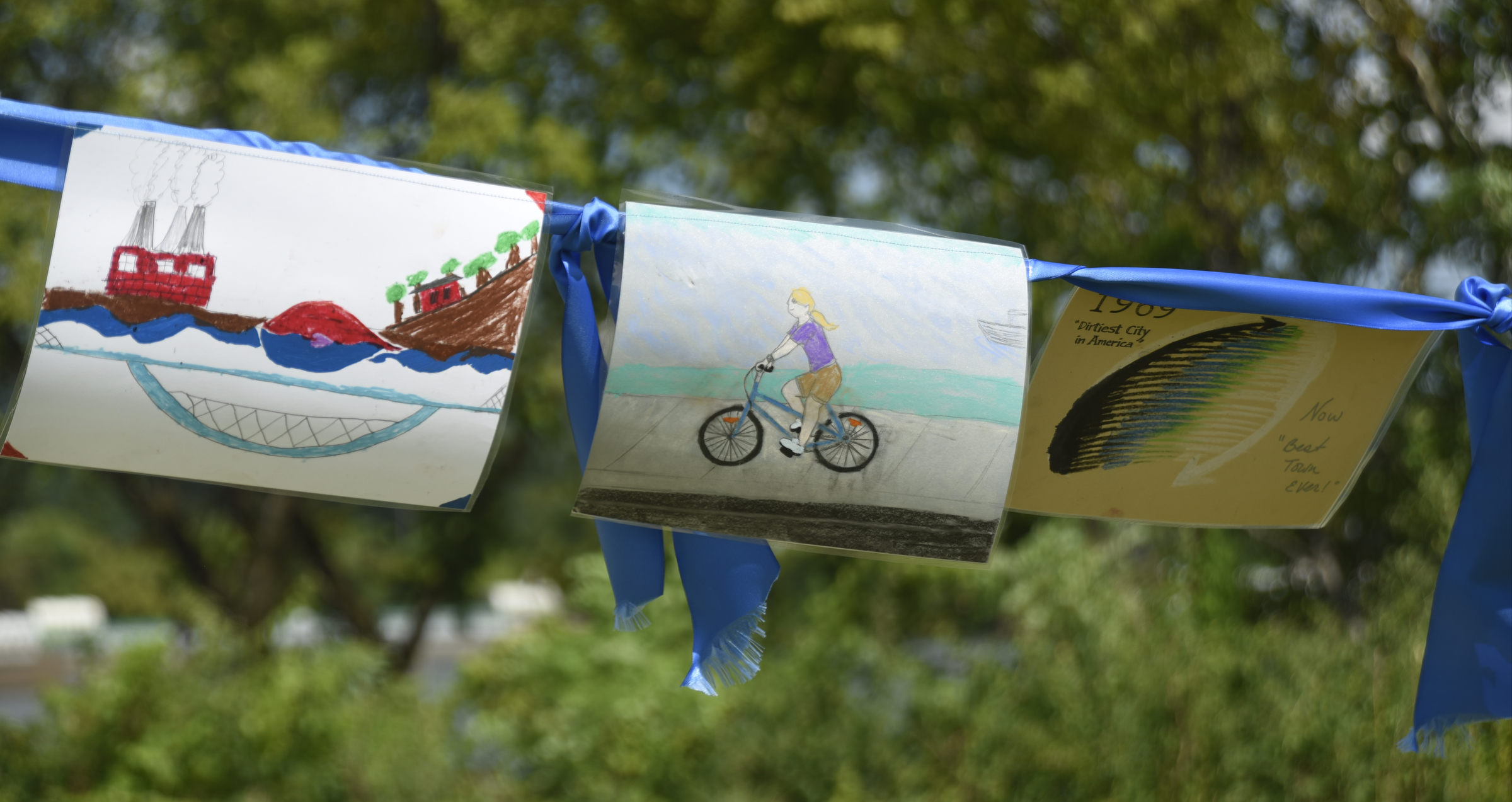 Drawings hang across the ribbon during the grand opening of the 3-mile extension of the Riverwalk Friday, August 12, 2016.