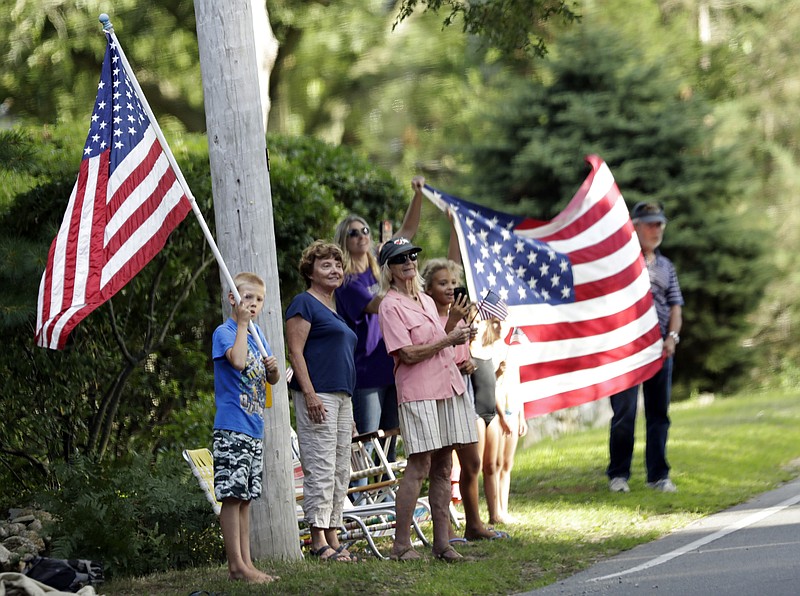 
              People wave the American flag as the presidential motorcade passes in White Haven, Mass., on Martha's Vineyard, Thursday, Aug. 11, 2016. (AP Photo/Manuel Balce Ceneta)
            
