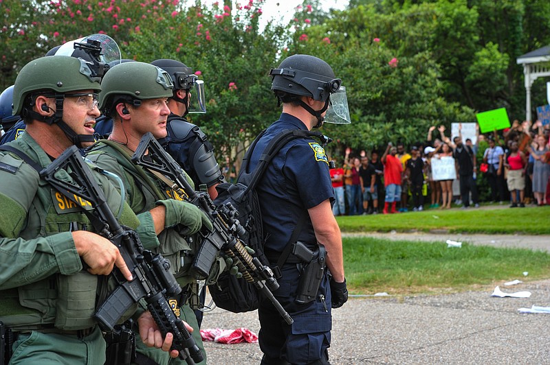 Police officers in Baton Rouge, La., warily watch two protester groups gather near each other last month.