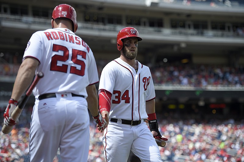 Washington Nationals' Bryce Harper (34) is greeted by Clint Robinson after he scored on a sacrifice fly by Anthony Rendon during the first inning of a baseball game against the Atlanta Braves, Sunday, Aug. 14, 2016, in Washington.