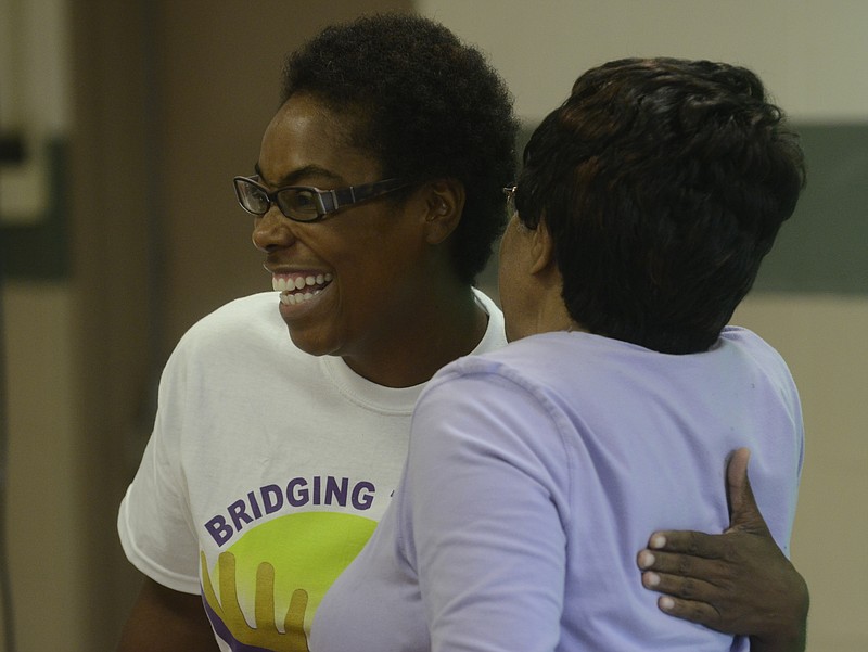 Demetrus Coonrod, left, hugs Mary Powell at Eastdale Recreation Center during a meeting to celebrate the Neighborhood Association's one year anniversary.