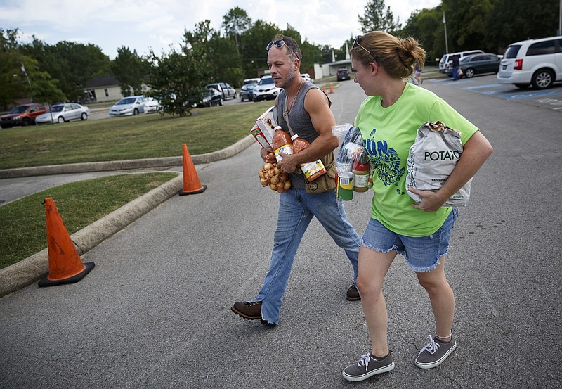 Caitlin Hill, right, helps Savalas Prater carry food to his car from the mobile pantry at Eastside Elementary on Wednesday, Aug. 17, 2016, in Chattanooga, Tenn. Principal Stephanie Hinton began a monthly food drive to help care for her students and to better involve parents.