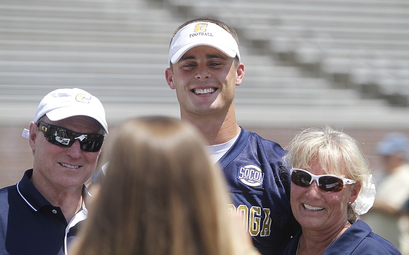 Quarterback B.J. Coleman {CQ}, center, poses for a picture with Dana Robinette {CQ}, left, and Suzan Robinette {CQ}, right, during Saturday's autograph session. The UTC Mocs held a "Meet the Mocs" autograph session before having a scrimmage at Finley Stadium on Saturday.