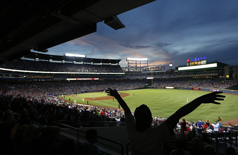 
              FILE - In this Saturday, July 30, 2016, file photo, a fan waves as the sun sets behind Turner Field during a baseball game between the Philadelphia Phillies and the Atlanta Braves in Atlanta. Turner Field, the home of the Atlanta Braves and the 1996 Olympics, will get its "third life" when Georgia State University converts it to a college football stadium, Atlanta city leaders said Thursday. (AP Photo/John Bazemore, File)
            
