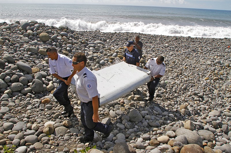 
              FILE - In this July 29, 2015, file photo, French police officers carry a piece of debris from a plane known as a "flaperon" on the shore of Saint-Andre, Reunion Island. An Australian official says experts hunting for the missing Malaysian airliner are attempting to define a new search area by studying where in the Indian Ocean the first piece of wreckage recovered from the lost Boeing 777 _ a wing flap _ most likely drifted from after the disaster that claimed 239 lives. (AP Photo/Lucas Marie, File)
            
