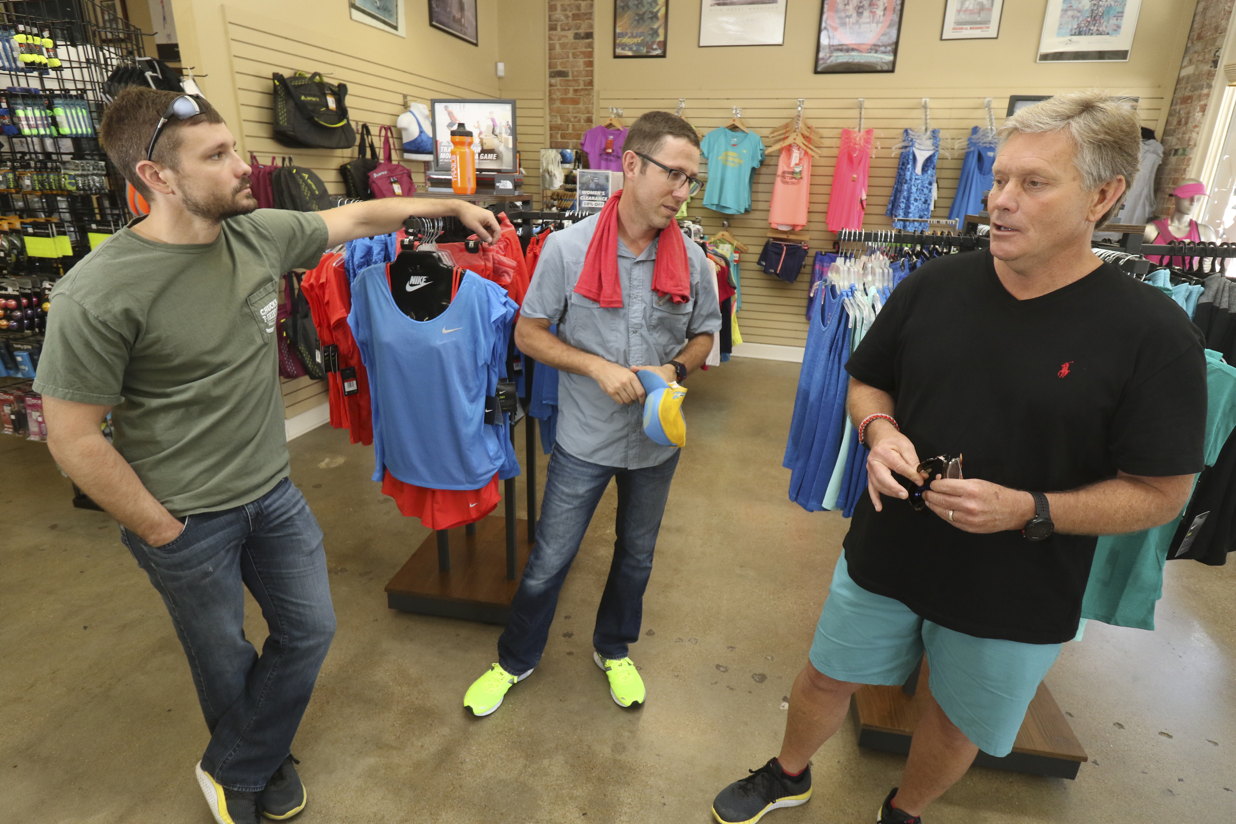 Staff Photo by Dan Henry / The Chattanooga Times Free Press- 8/18/16. Chris Bean, left, and Steve Bean, right,speak to Alan Outlaw about next weekend's Cam Run honoring the late Cameron Bean while in Outlaw's running store on Thursday, August 18, 2016 .
