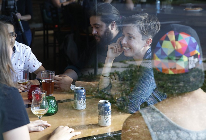 Diana Downard, 26, a Bernie Sanders supporter who now says she will vote for Hillary Clinton, has drinks with friends at a pub in Denver on July 6, 2016. "Millennials have been described as apathetic, but they're absolutely not," says Downard "Millennials have a very nuanced understanding of the political world." (AP Photo/Brennan Linsley)