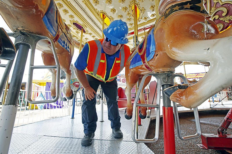 
              In this Tuesday, Oct. 6, 2015 file photo, amusement device inspector Avery Wheelock inspects the safety pins on a children's merry-go-round at the Mississippi State Fair in Jackson, Miss. In some parts of the U.S., the thrill rides that hurl kids upside down, whirl them around or send them shooting down slides are checked out by state inspectors before customers climb on. But in other places, they are not required to get the once-over. (AP Photo/Rogelio V. Solis, File)
            