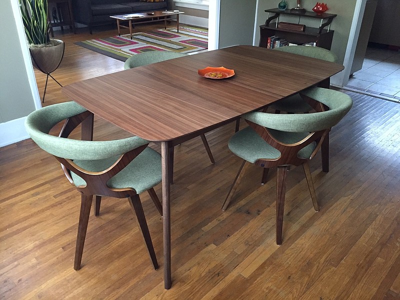 A walnut table with built-in leaf paired with 1960s-style chairs with curved wooden backs and green upholstery complements a home's vintage and midcentury modern vibe.