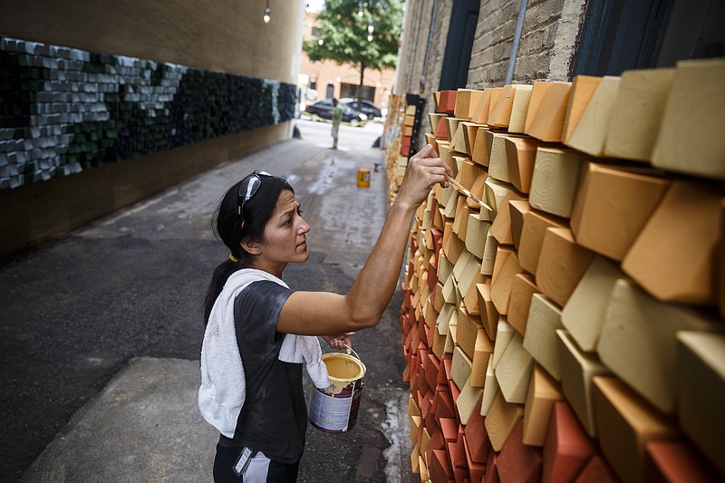 Jennifer Hiser puts the finishing touches on the Neural Alley art installation in the alley connecting Chestnut Street and Broad Street on Wednesday, Aug. 24, 2016, in Chattanooga, Tenn. The alley is one of 4 in the city where interactive art installations were placed for the Passageways project.