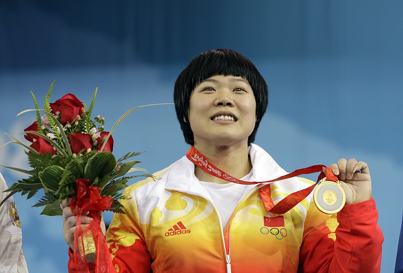 
              FILE - In this Wednesday, Aug. 13, 2008, file photo, Liu Chunhong, of China displays her gold medal in the women's 69 kg of the weightlifting competition at the Beijing 2008 Olympics in Beijing, China. The International Weightlifting Federation on Wednesday, Aug. 24, 2016, said that 11 2008 Olympic athletes tested positive in retests, including Liu, for a range of banned substances in the latest scandal to shake the sport, which is already processing retests which caught numerous medalists from the 2008 and 2012 games. (AP Photo/Andres Leighton, file)
            