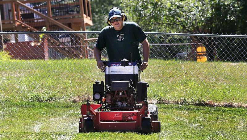 In this Monday, Aug. 22, 2016, photo, Jake Wilson, owner of Top Class Lawn Care, mows a lawn on a job in Kansas City, Mo. Wilson is on the fence about his 5-year-old company and whether he should add to his staff of three and buy another truck. Wilson is concerned that if he does expand, he won’t be giving his customers the kind of service he does now. (AP Photo/Orlin Wagner)
