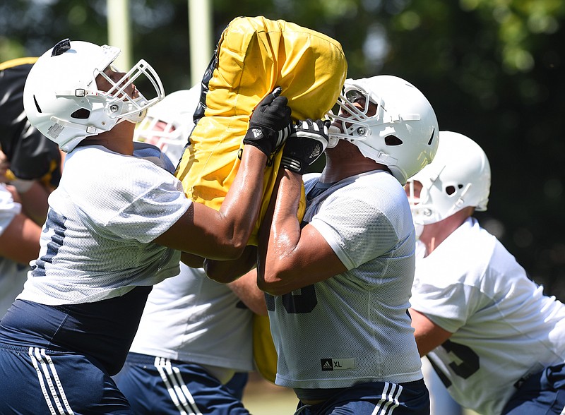 Staff photo by Tim Barber Mocs offensive linemen Kennington Cadwell (57), left, and Malcolm White (56), face off on the offensive line in a feet, hips and finish drill on the first day of Mocs football practice at Scrappy Moore Field.