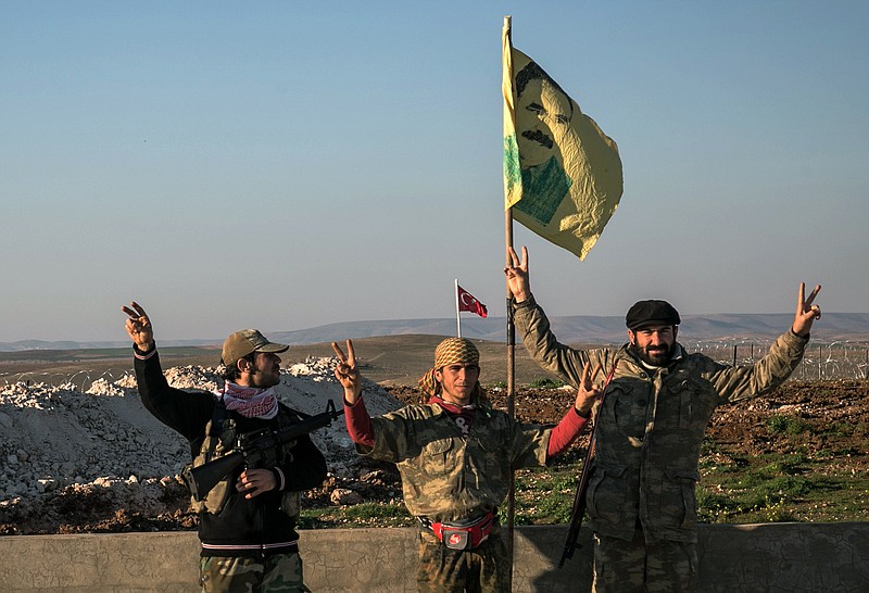 
              FILE - In this Feb. 22, 2015 file photo, Syrian Kurdish militia members of the YPG make a V-sign next to a drawing of Abdullah Ocalan, jailed Kurdish rebel leader, in Esme village in Aleppo province, Syria. A Turkish military expedition into Syria has threatened a Kurdish political project just as Kurdish forces seemed on the verge of connecting their northern Syrian zones. It is the first Turkish ground intervention in the course of the Syria war, now in its sixth year, and it underscores how seriously Turkey is taking Kurdish autonomy next door. (Mursel Coban/Depo Photos via AP, File)
            