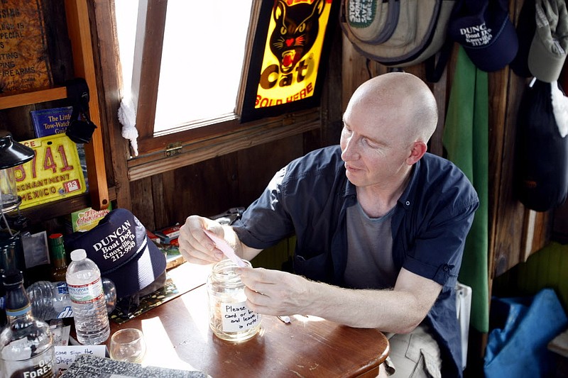 
              In this Aug. 8, 2016 photo, ships' mate Adrian Nankivell reads through handwritten messages left during an open house of the shantyboat Dotty, which is floating down the Tennessee River this summer as part of an oral history project called "A Secret History of American River People." in Florence, Ala.  Smack dab in the middle of the Tennessee River near Muscle Shoals, Alabama, a recreated relic of river history is stuck like a catfish on a line, its anchor snagged on God only knows what at the bottom of the river. The shantyboat Dotty is a floating art project crafted by California-based artist Wes Modes.(Dennis Pillion/AL.com via AP)
            