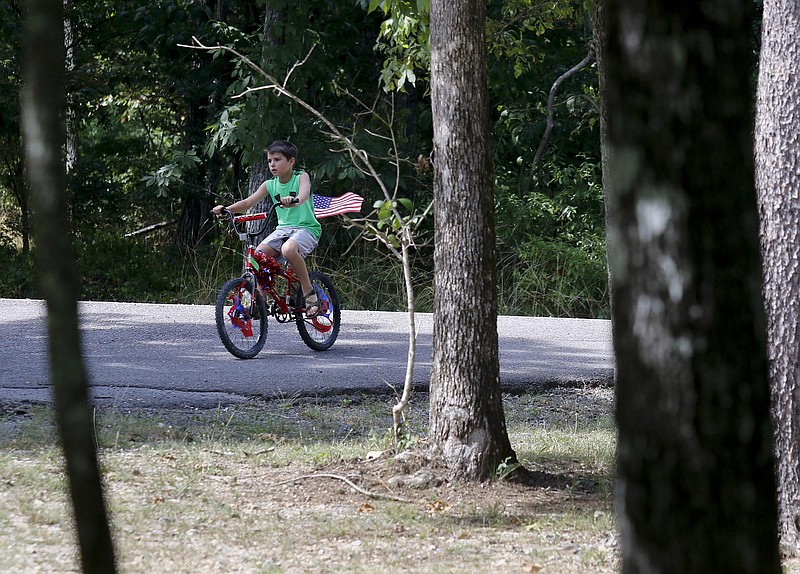 A boy rides with an American flag on his bicycle during an Independence Day Parade at DeSoto State Park.