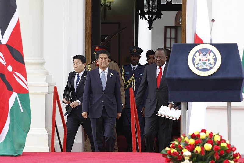 
              Japan's Prime Minister Shinzo Abe, centre, and Kenyan President, Uhuru Kenyatta, right, walk together to present a joint press conference outside State House, in Nairobi. Kenya Friday, Aug. 26, 2016.  Abe is in Kenya for an official visit. (AP Photo/Khalil Senosi)
            