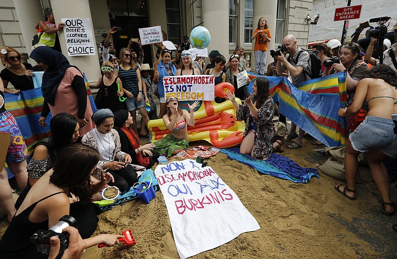 
              Activists protest outside the French embassy, during the "wear what you want beach party" in London, Thursday, Aug. 25, 2016. The protest is against the French authorities clampdown on Muslim women wearing burkinis on the beach. Writing on the sign reads: 'No to Islamophobia, yes to Burkinis.' (AP Photo/Frank Augstein)
            