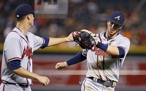 Atlanta Braves' Matt Wisler, left, slaps gloves with Dansby Swanson, right, after Swanson made a long throw from deep shortstop to get Arizona Diamondbacks' Mitch Haniger out at first base during the fourth inning of a baseball game Thursday, Aug. 25, 2016, in Phoenix. (AP Photo/Ross D. Franklin)