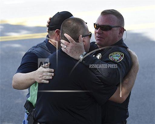 Maryville Police Department Detective John Foley, right, hugs Blount County Sheriff's Office investigators Andy Waters, center, and Joey Parton after the body of slain police officer Kenny Moats passed in a procession Friday, Aug. 26, 2016, in Maryville, Tenn. The nine-year veteran officer was killed Thursday after he was shot while answering a domestic violence call. Brian Keith Stalans, 44, was taken into custody after the shooting and is being held for investigation pending charges that will likely be placed Friday, according to the Blount County Sheriff's Office. (Amy Smotherman Burgess/Knoxville News Sentinel via AP)