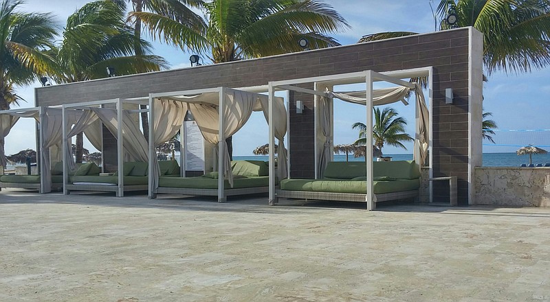 Poolside beds offer a good deal more comfort than a lounge chair on the beach at Wyndham Fortuna in the Bahamas, above. At left, guests take a siesta in the shade of a large palm at Sandals Emerald Bay.