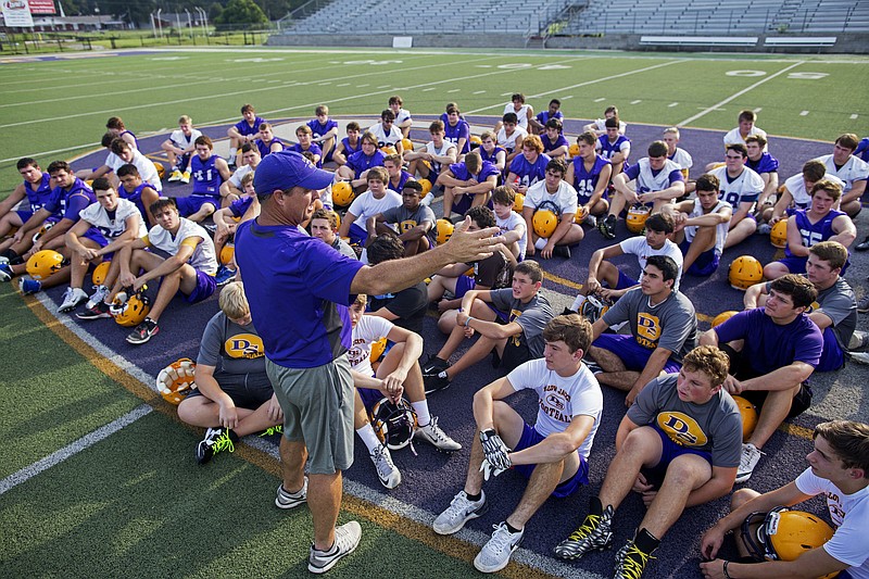 
              Denham Springs High School football coach Dru Nettles talks to his team at the start of the team's first practice after the flood in Denham Springs, La., Wednesday, Aug. 24, 2016. Nettles sat the team down on the purple logo at midfield and asked his players if they saw the aerial photographs of their inundated school. "If you look at the back of campus, the one thing that didn't go underwater was this logo," Nettles said. "Awesome sign right there that this 'DS' was shining ... to give people hope." (AP Photo/Max Becherer)
            