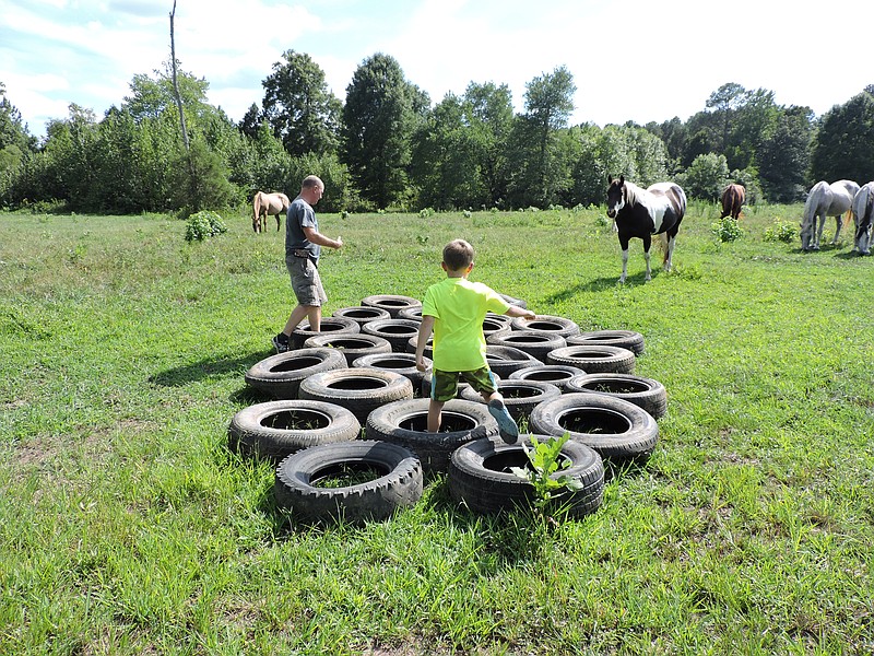 Max Harden, 7, runs through a tire obstacle that's part of the Cowboy Church Mud Run course.