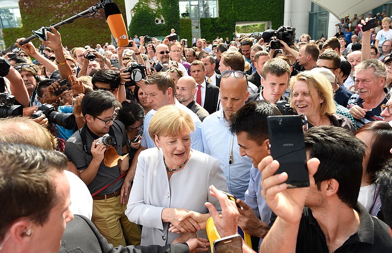 
              German Chancellor Angela Merkel greets members of the public at the Federal Chancellery during the 18th open day of the German Federal Government in Berlin, Germany, Sunday Aug. 28,  2016. (Rainer Jensen/dpa via AP)
            