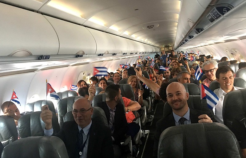 
              JetBlue flight 387 passengers hold up representations of Cuba's national flag, just before touching down at the airport in Santa Clara, Cuba, Wednesday, Aug. 31, 2016. JetBlue 387, the first commercial flight between the U.S. and Cuba in more than a half century, landed in the central city of Santa Clara on Wednesday morning, re-establishing regular air service severed at the height of the Cold War. (AP Photo/Michael Weissenstein)
            