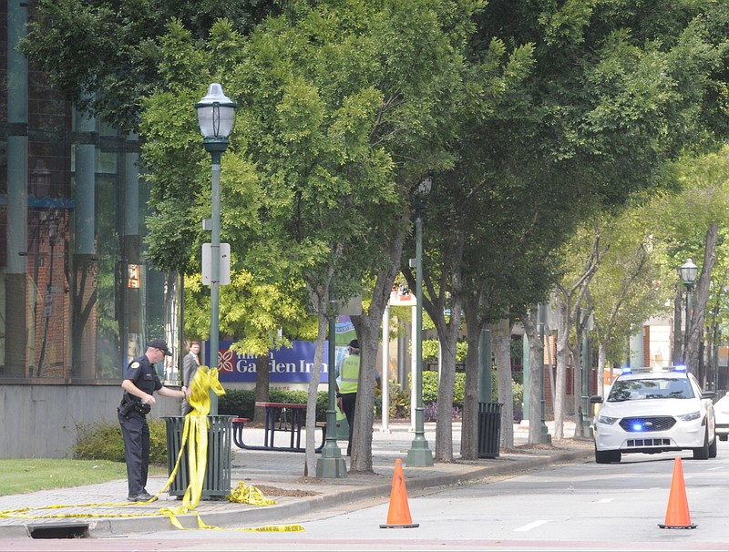 Chattanooga police remove yellow tape after using a water cannon on the trash can at the corner of 4th and Chestnut streets shortly before 3 p.m. on Thursday. A report of a suspicious black cylinder in front of the Creative Discovery Museum turned out to be an empty camera lens case.