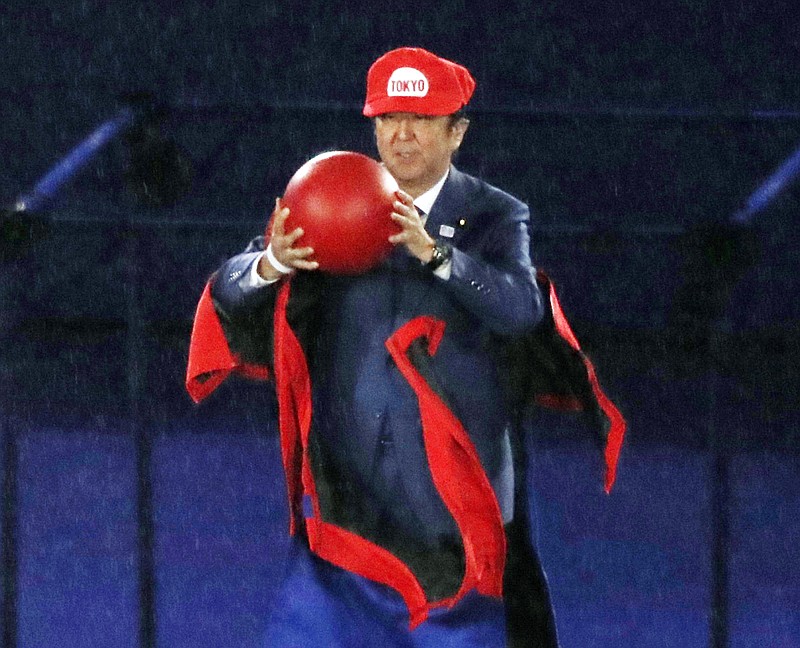 
              FILE - In this Aug. 21, 2016 file photo, Japanese Prime Minister Shinzo Abe removes costume of the Nintendo game character Super Mario as he makes an appearance during the closing ceremony at the 2016 Summer Olympics in Rio de Janeiro, Brazil. How much yen did Nintendo pay to land that dream marketing opportunity at the Rio Olympics closing ceremony when Japan’s prime minister popped out dressed as the red-hatted plumber Super Mario? Zero. (Masanori Takei/Kyodo News via AP, File)
            