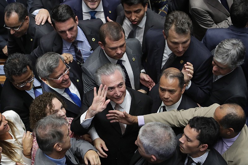 
              In this Wednesday, Aug. 31, 2016 photo, Brazil's President Michel Temer, center, is surrounded by senators as he arrives to take the presidential oath at the National Congress, in Brasilia, Brazil. Several dozen of the lawmakers who voted earlier in the day to remove President Dilma Rousseff are under investigation in the scandal involving billions of dollars of kickbacks. Rousseff has charged that corrupt lawmakers wanted her out to halt the Petrobras probe. But if the intention was to sweep the probe under the rug, it’s too late, say law professors, corruption experts and political analysts. (AP Photo/Eraldo Peres)
            