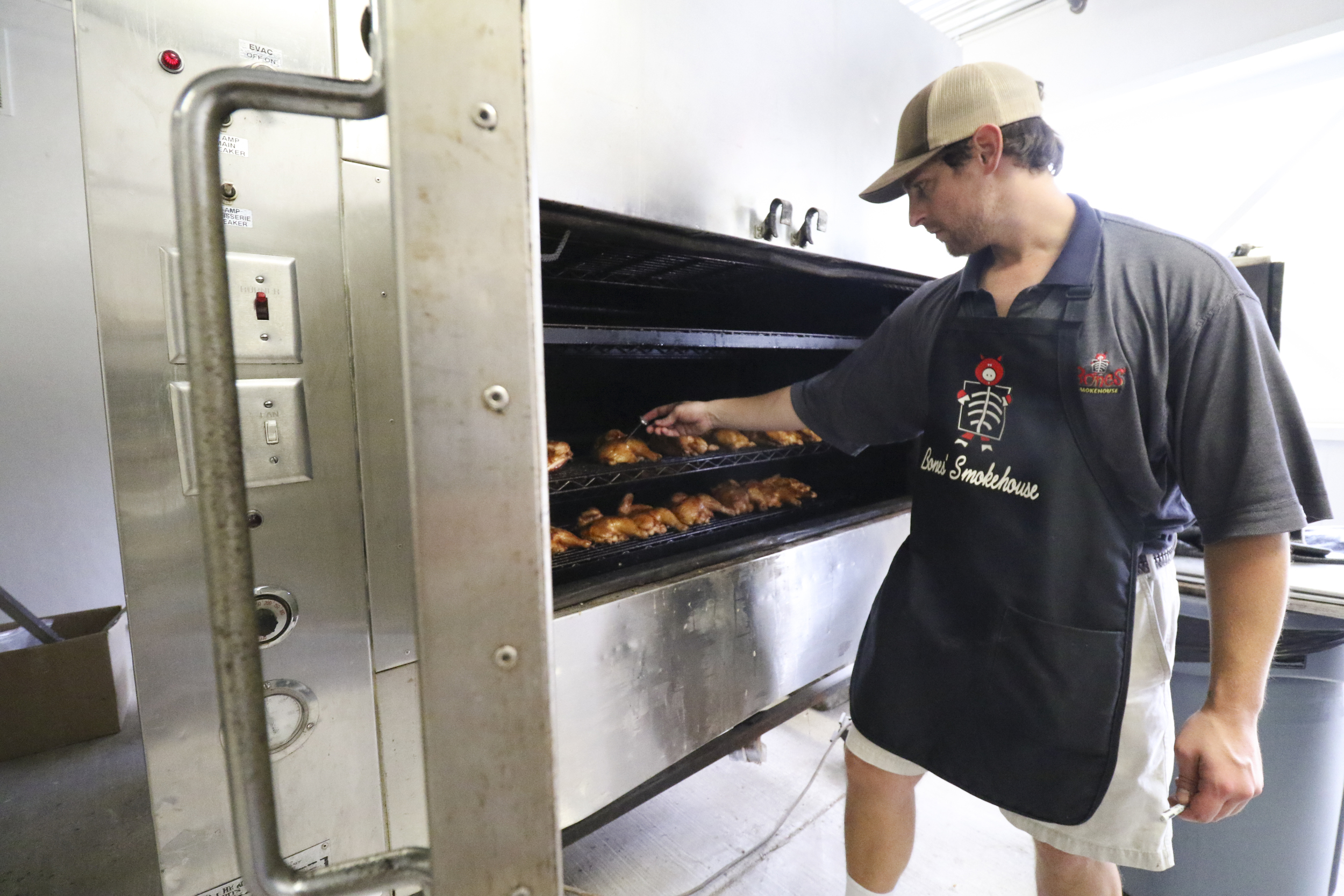 Bones Smokehouse restaurant manager Andrew Hennen checks the temperature of chicken in the smoker.