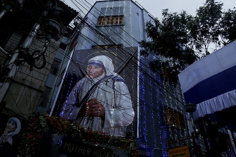 Mother House of the Missionaries of Charity group founded by Mother Teresa is illuminated with a huge portrait of her displayed in Kolkata, India, Sunday, Sept. 4, 2016. Pope Francis declared Mother Teresa a saint on Sunday, praising the tiny nun for having taken in society's most unwanted and for having shamed world leaders for the "crimes of poverty they themselves created." (AP Photo/Bikas Das)