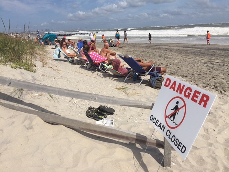 People sit at the beach in Ocean City, N.J., on Sunday, Sept. 4, 2016. Storm system Hermine spun away from the U.S. East Coast on Sunday, removing the threat of heavy rain but maintaining enough power to churn dangerous waves and currents — and keep beaches off-limits to disappointed swimmers and surfers during the holiday weekend.