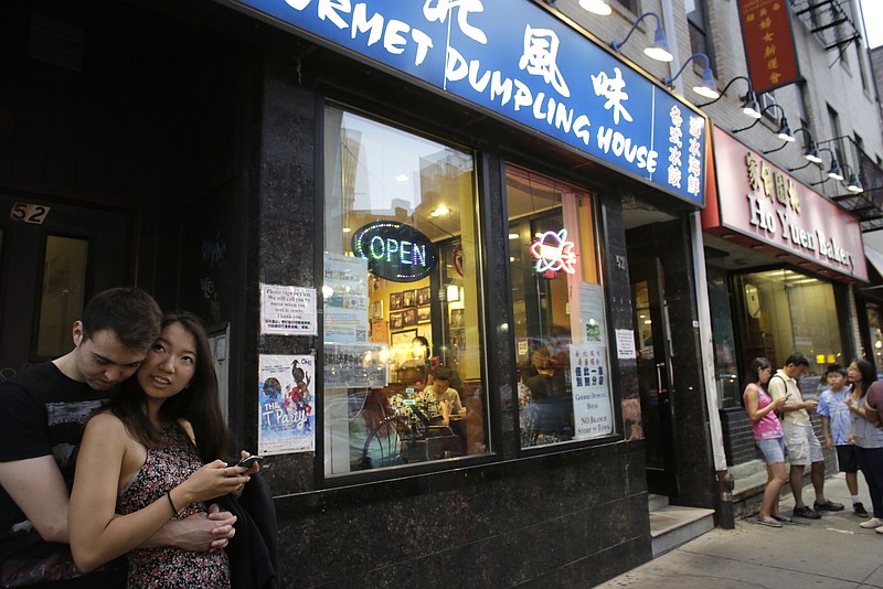 
              In this Monday, Aug. 29, 2016 photo a couple waits outside a restaurant in Boston's Chinatown neighborhood. Artist Wen-ti Tsen, who plans to install life-sized portraits on the street around the neighborhood beginning Sept. 10, says they're meant to underscore how the city's building boom is displacing longtime residents and businesses in the historic downtown enclave. (AP Photo/Steven Senne)
            