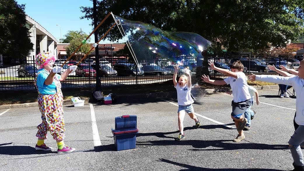 Children in Cartersville make large bubbles with the help of a clown.