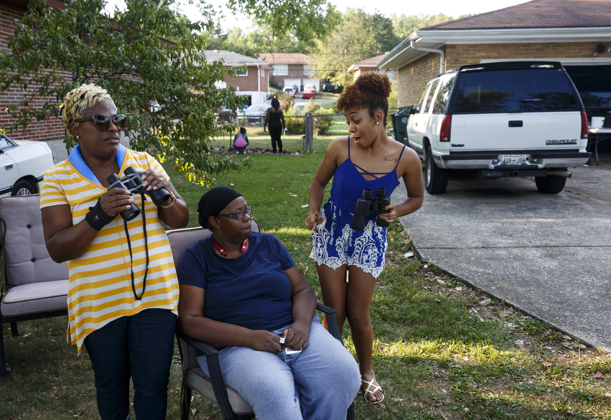 Diane Parker, left, LaShaunda Hammonds, center, and Gabrielle Mott prepare to use binoculars to watch a performance by artist Usher at Dalewood Middle School from the yard of a home across the street after they could not secure entry wristbands on Friday, Sept. 9, 2016, in Chattanooga, Tenn. The concert concluded a string of activities and benefits by the artist in his home town.